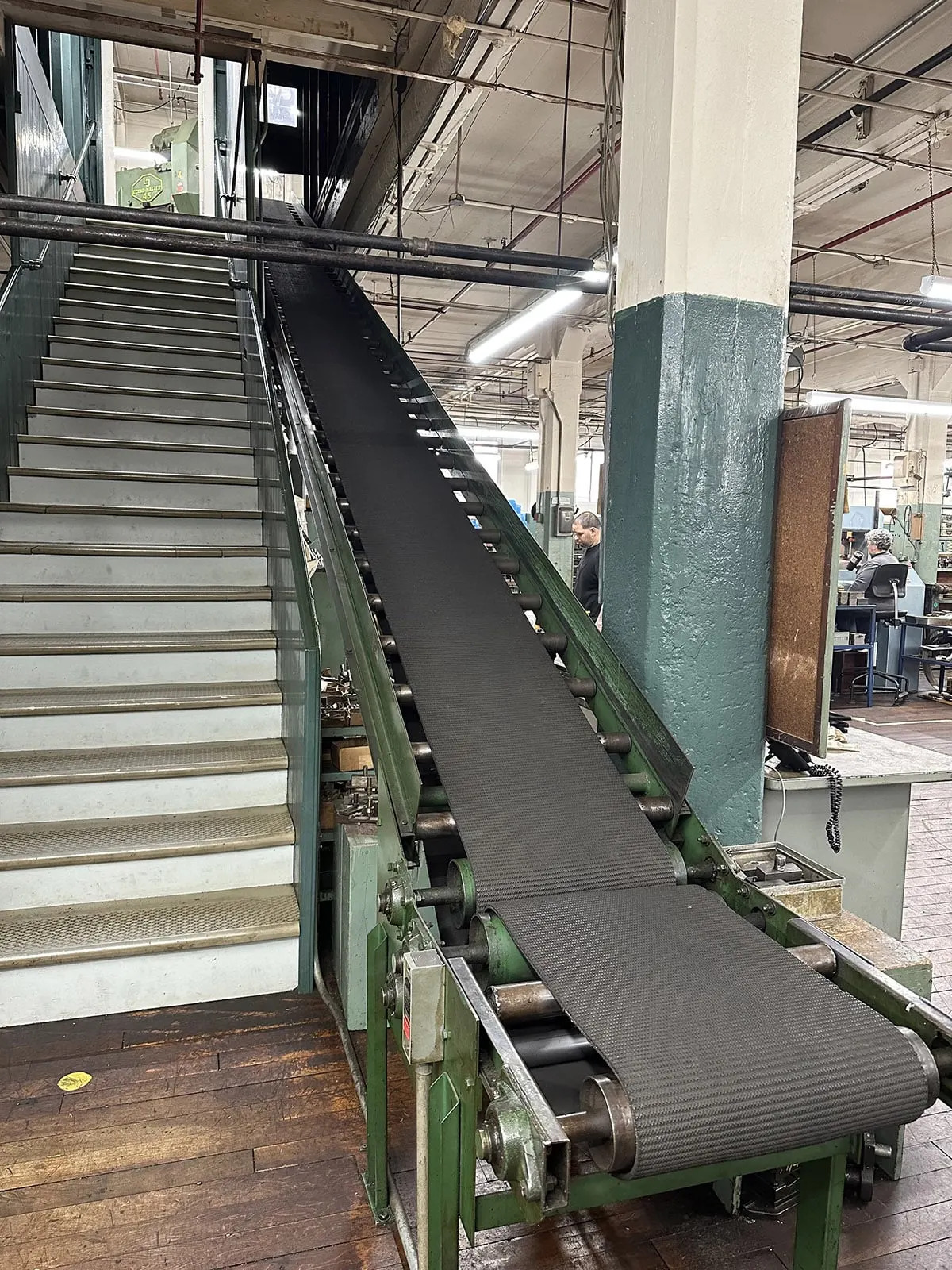 A parts conveyor running alongside a stairway on the shop floor