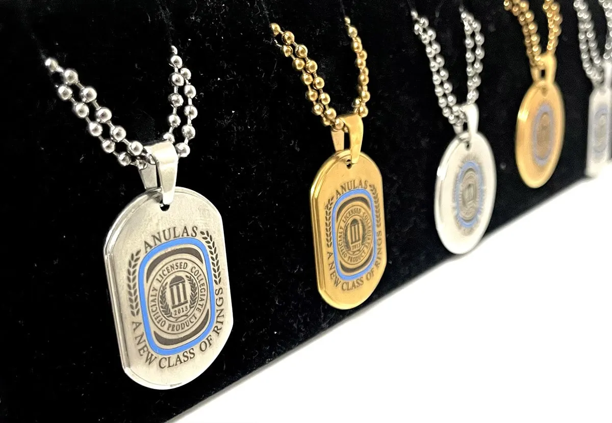 Die-struck pendants on ball chains in silver and gold finishes, displayed on black velvet