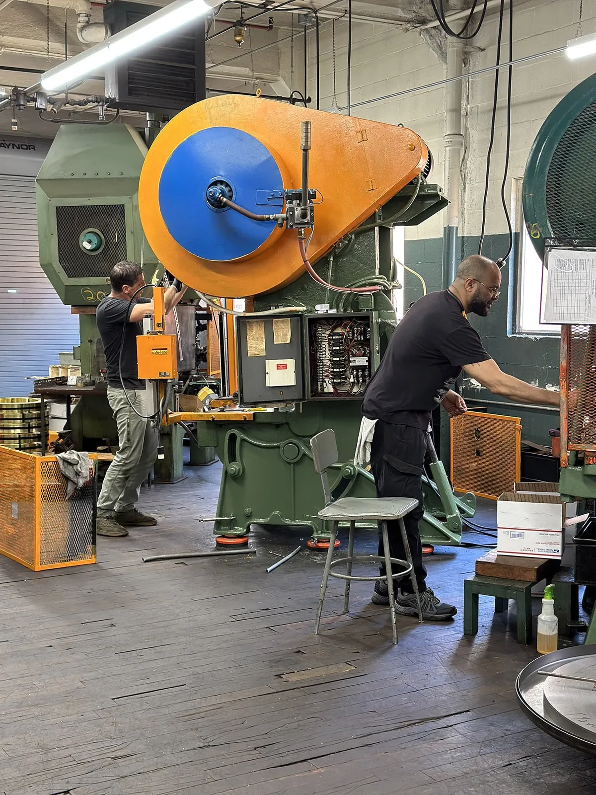 Operators setting up a large mechanical stamping press on the shop floor